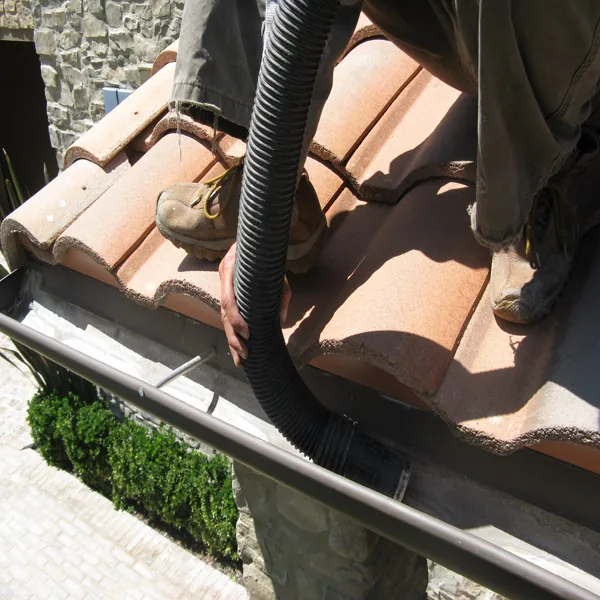 Vacuum hose at a tile roof and gutter